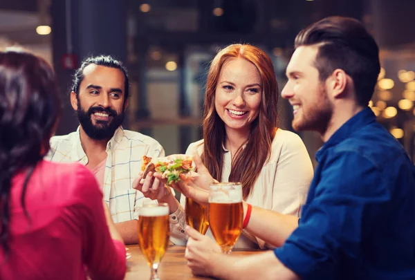 Amigos comendo pizza com cerveja no restaurante — Fotografia de Stock