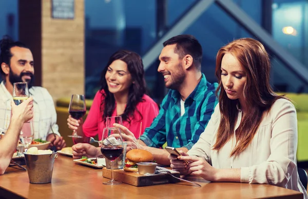 Mujer con smartphone y amigos en el restaurante — Foto de Stock