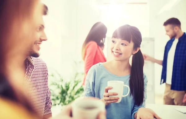 Lyckliga kreativa team dricker kaffe på kontoret — Stockfoto