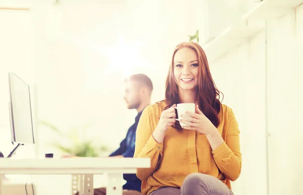 Mulher feliz bebendo café ou chá no escritório — Fotografia de Stock
