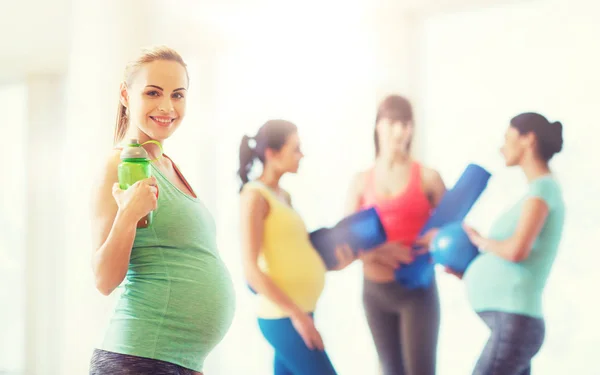 Felice donna incinta con bottiglia d'acqua in palestra — Foto Stock