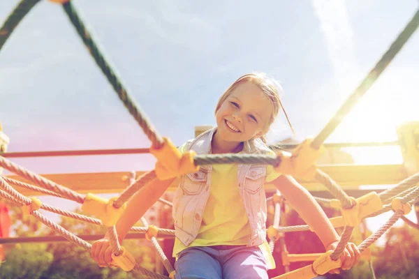 Fröhliches kleines Mädchen klettert auf Kinderspielplatz — Stockfoto