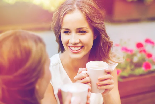 Mujeres jóvenes sonrientes con tazas de café en la cafetería —  Fotos de Stock