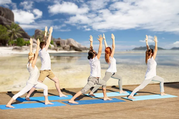 Gruppe von Leuten, die Yoga-Übungen am Strand machen — Stockfoto