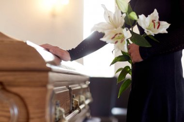 woman with lily flowers and coffin at funeral clipart