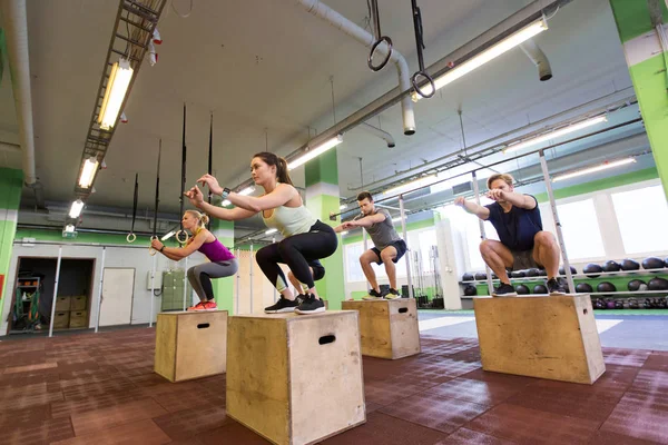 Grupo de personas haciendo ejercicios de salto de caja en el gimnasio — Foto de Stock
