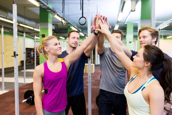 Grupo de amigos felices haciendo cinco en el gimnasio — Foto de Stock