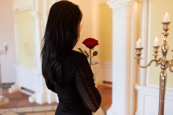 Mujer triste con rosa roja en el funeral en la iglesia —  Fotos de Stock