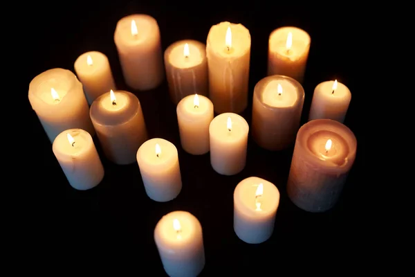 Свічки, що горять у темряві над чорним тлом — стокове фото