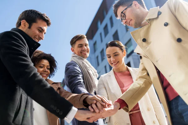 Groep van gelukkige mensen hand in hand in de stad — Stockfoto