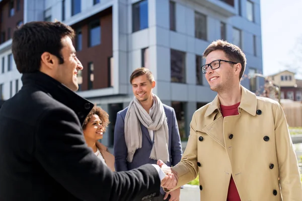 Happy people shaking hands on city street — Stock Photo, Image