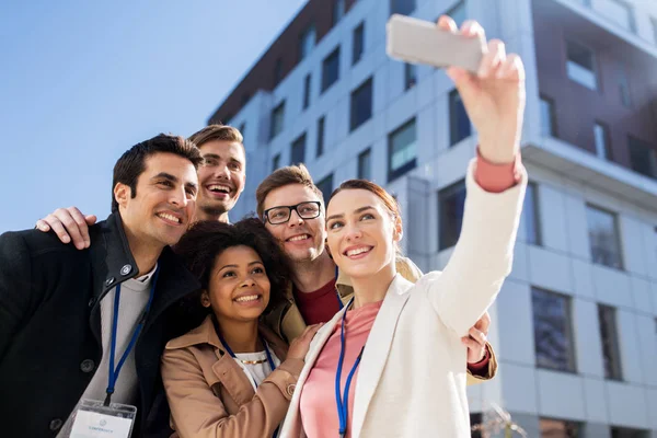 Šťastní lidé s konference odznaky s selfie — Stock fotografie