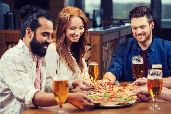 Друзі їдять піцу з пивом в ресторані — стокове фото