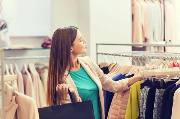 Feliz jovem mulher escolhendo roupas no shopping — Fotografia de Stock