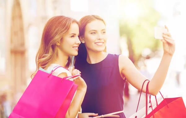 Mulheres felizes com sacos de compras e smartphone — Fotografia de Stock