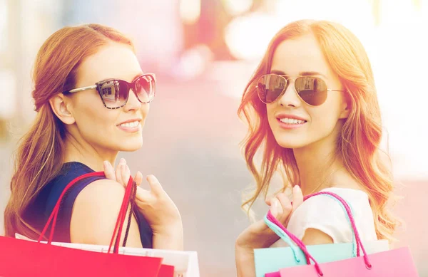 Jovens mulheres felizes com sacos de compras na cidade — Fotografia de Stock