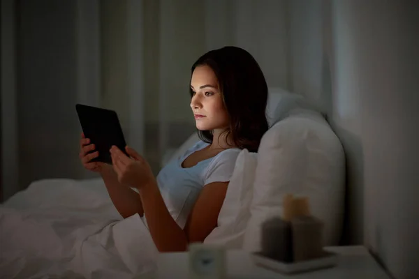 Wanita muda dengan tablet pc di tempat tidur di kamar tidur rumah — Stok Foto