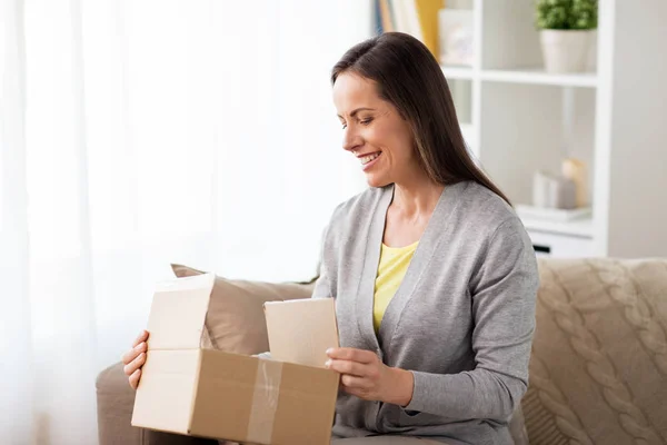 Mujer sonriente abriendo caja de cartón — Foto de Stock