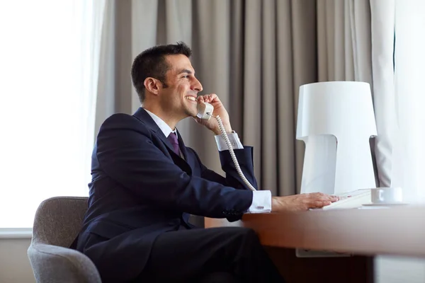 Uomo d'affari che chiama alla scrivania in camera d'albergo — Foto Stock