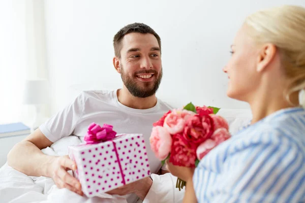 Gelukkige paar met de doos van de gift in bed thuis — Stockfoto
