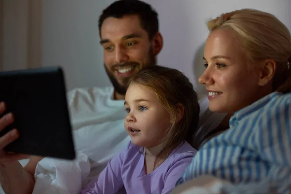 Familia feliz con la tableta PC en la cama en casa —  Fotos de Stock