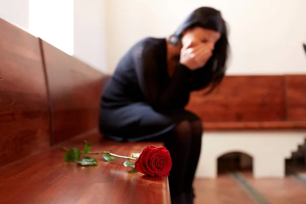 Weinende Frau mit roter Rose bei Beerdigung in Kirche — Stockfoto