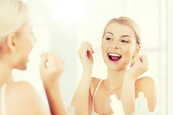 Mujer con hilo dental limpieza de dientes en el baño — Foto de Stock