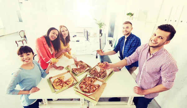 Equipe de negócios feliz comer pizza no escritório — Fotografia de Stock