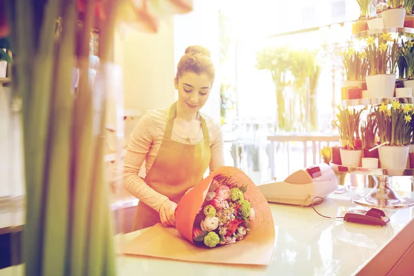 Sonriente florista mujer embalaje ramo en floristería — Foto de Stock