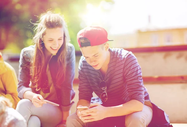 Happy teenage friends with smartphones outdoors — Stock Photo, Image