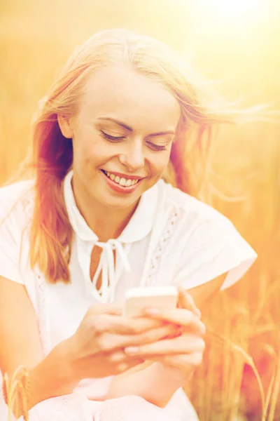 Счастливая молодая женщина со смартфоном на зерновом поле — стоковое фото