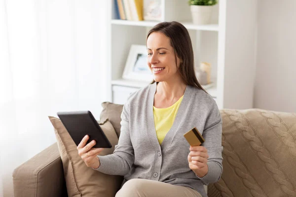 Щаслива жінка з планшетом і банківською картою вдома — стокове фото