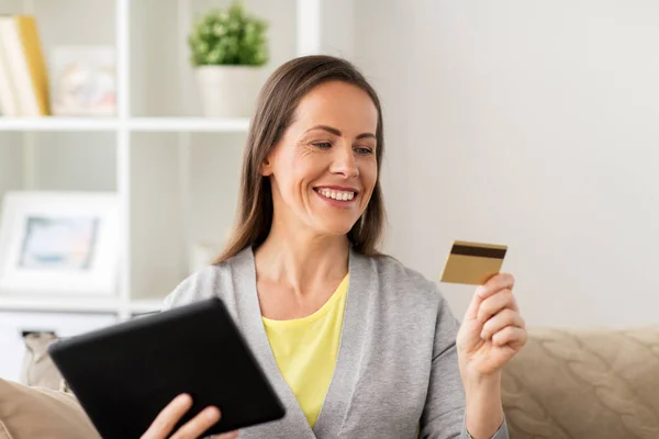 Szczęśliwa kobieta z tablet pc i banku karty w domu — Zdjęcie stockowe