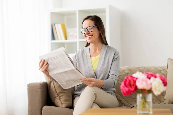 Счастливая женщина, читающая газету дома — стоковое фото