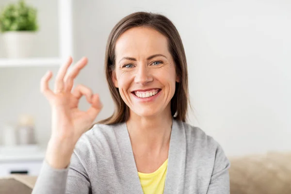 Glad leende kvinna visar ok hand tecken hemma — Stockfoto