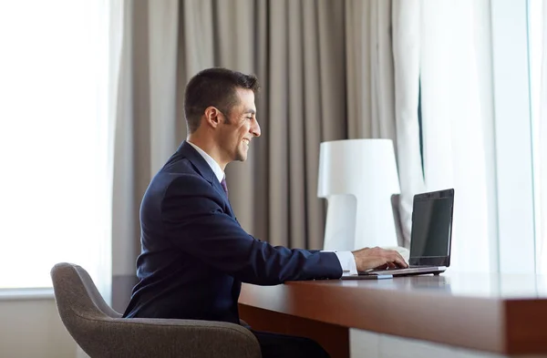 Hombre de negocios escribiendo en el ordenador portátil en la habitación de hotel — Foto de Stock