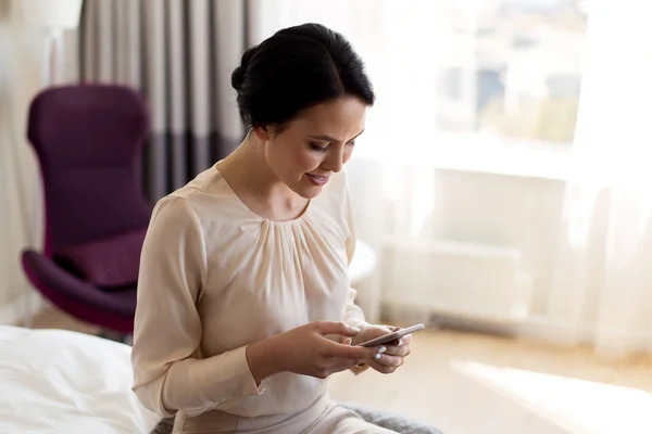 Mujer de negocios feliz con teléfono inteligente en la habitación de hotel —  Fotos de Stock