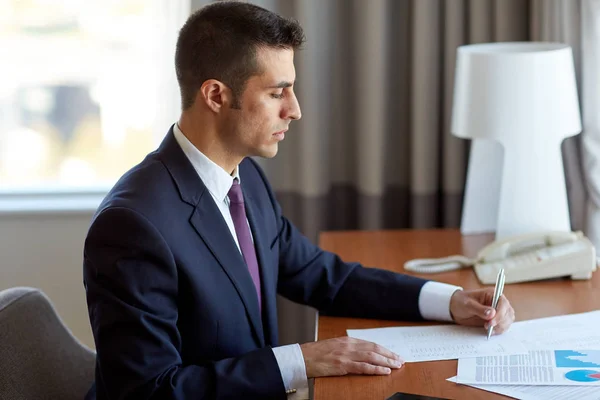 Hombre de negocios con papeles trabajando en la habitación del hotel —  Fotos de Stock