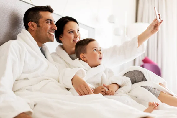 Otel odasında yatakta smartphone ile mutlu aile — Stok fotoğraf