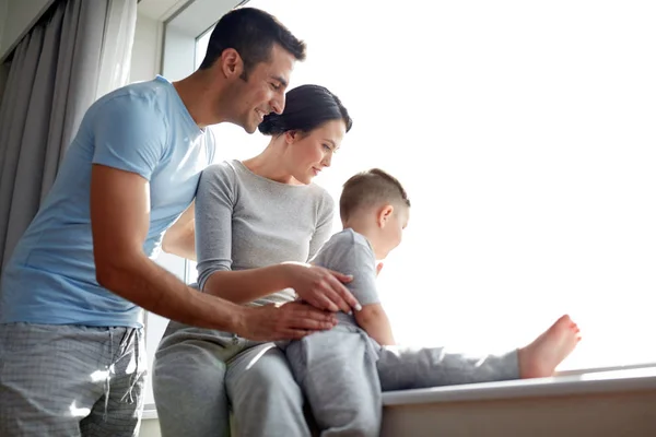 Gelukkige familie op zoek via venster thuis — Stockfoto