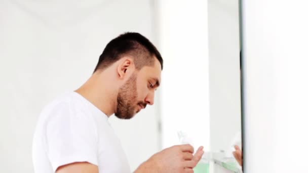 Hombre feliz aplicando aftershave a cara en el baño — Vídeo de stock