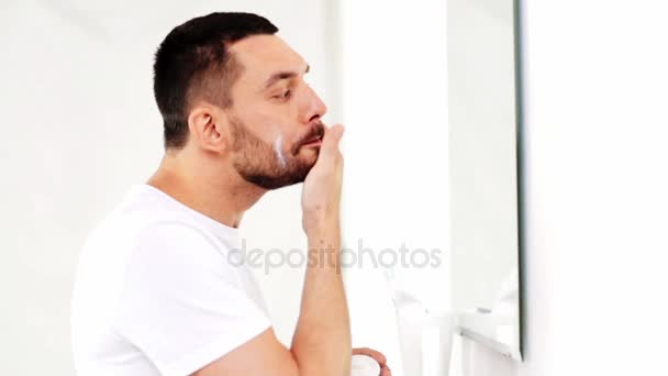Feliz jovem aplicar creme de rosto no banheiro — Vídeo de Stock