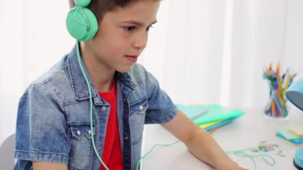 Αγόρι με ακουστικά που παίζει βιντεοπαιχνίδι στο laptop — Αρχείο Βίντεο