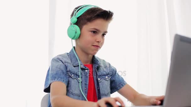 Kulaklıklı çocuk dizüstü bilgisayarında video oyunu oynuyor. — Stok video