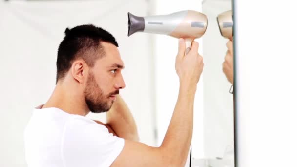 Hombre con ventilador secándose el pelo en el baño — Vídeos de Stock