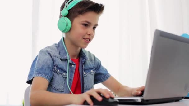 Niño en auriculares jugando videojuego en el ordenador portátil — Vídeos de Stock