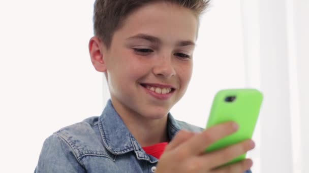 Menino sorridente feliz com smartphone em casa — Vídeo de Stock