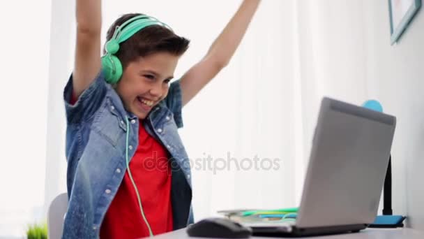 Jongen in hoofdtelefoon spelen video game op laptop — Stockvideo