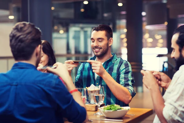 Amigos felizes tirando fotos de comida no restaurante — Fotografia de Stock