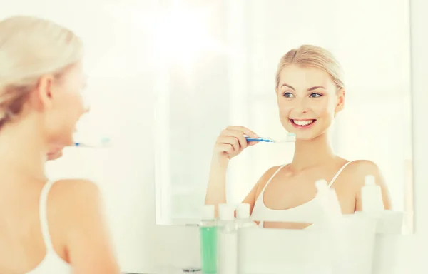 Woman with toothbrush cleaning teeth at bathroom — Stock Photo, Image